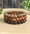 Natural amber and brown wood bead stacking bracelet set with three bracelets featuring natural wood grain patterns