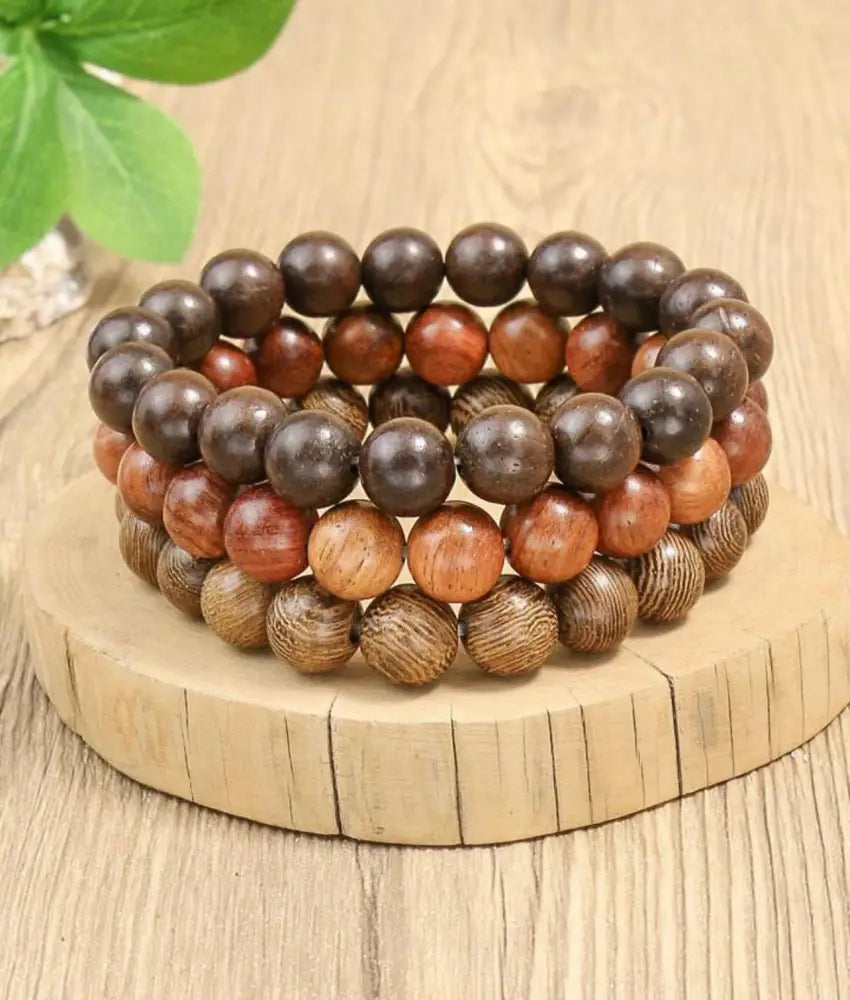 A set of three natural amber and brown wood bead stacking bracelets featuring round beads with wood grain patterns