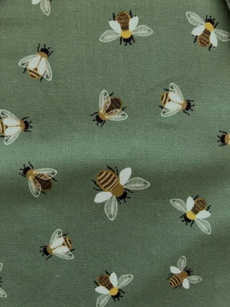 Olive green cotton bow top featuring a vintage bee print pattern with yellow and brown striped bodies and white wings