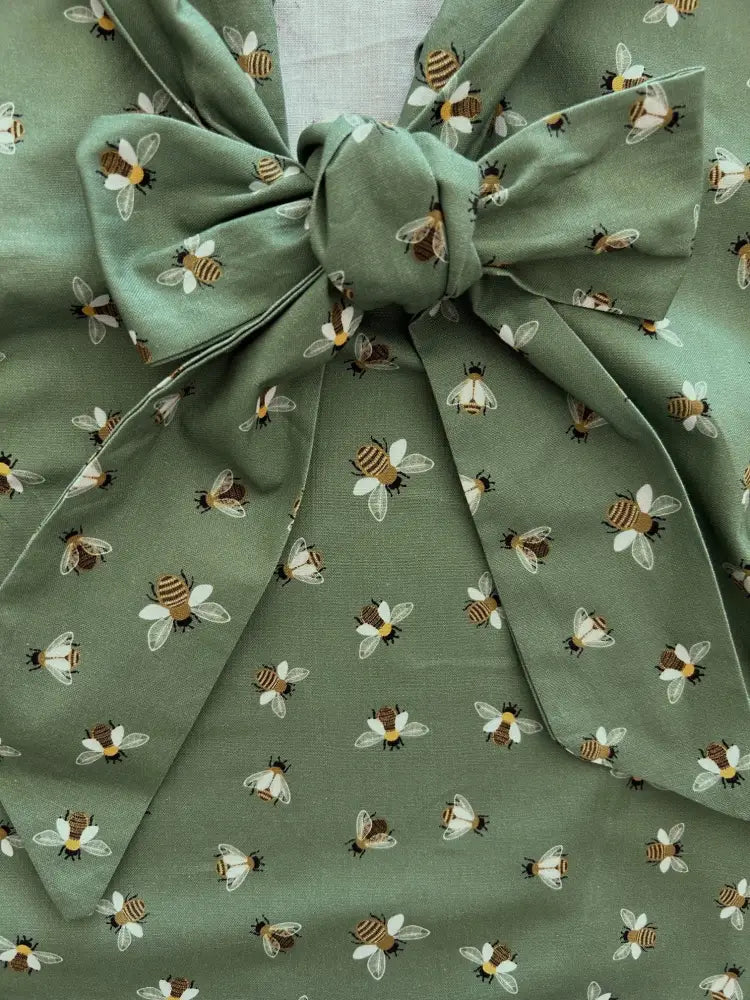 Vintage bee print cotton bow top in olive green featuring sage green fabric with a repeating illustrated bee pattern