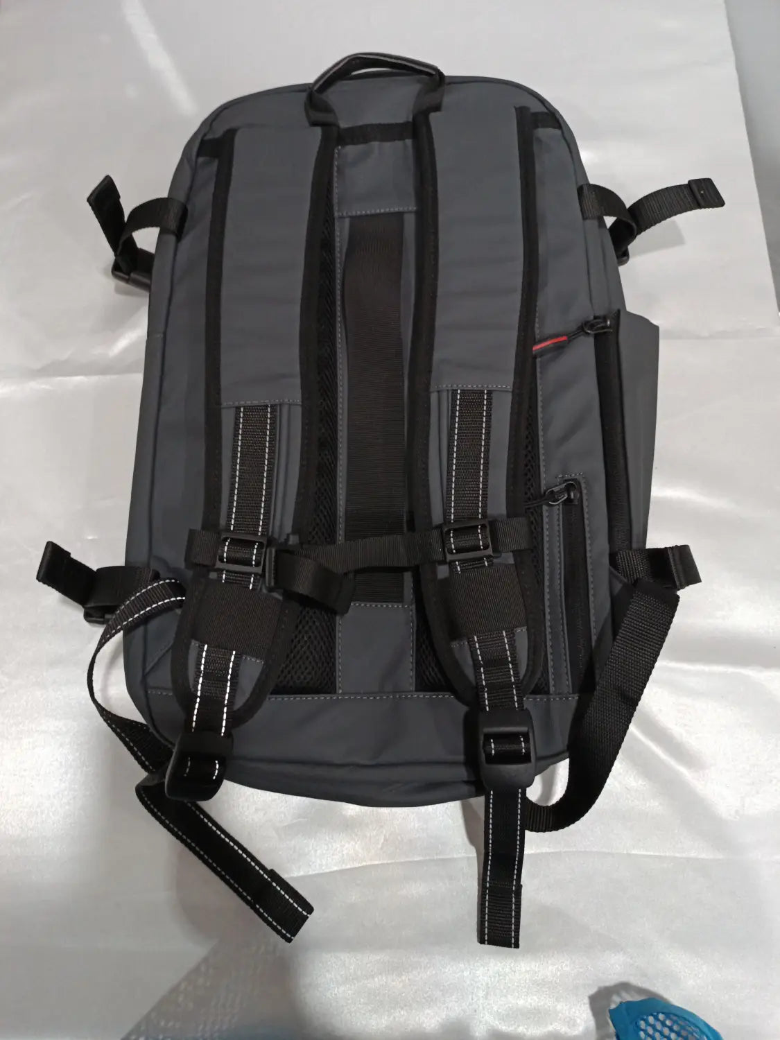Dark gray travel backpack with black straps and white stitching featuring a structured design and multiple adjustable buckles for vacuum compression and business laptop use.