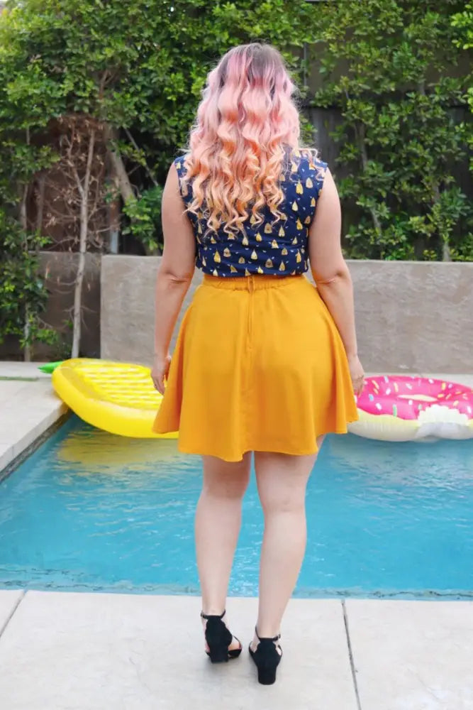 A vibrant yellow pleated a-line skirt with a fitted waistband paired with a vintage beehive print bow neck blouse