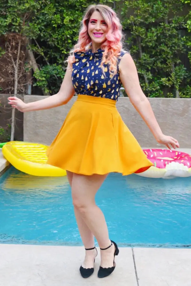 A vibrant yellow cotton pleated skirt with high waistband paired with a vintage beehive print bow neck sleeveless blouse