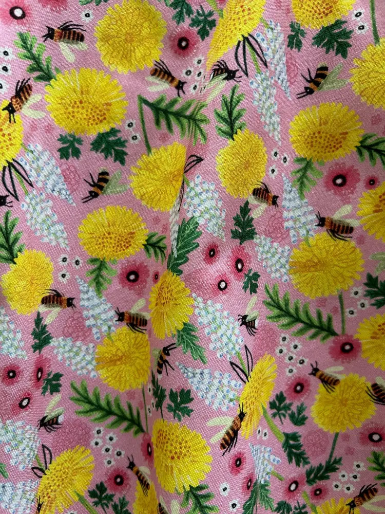Pink cotton skater skirt with vibrant yellow dandelions, pink flowers, green leaves, and black and yellow bees pattern