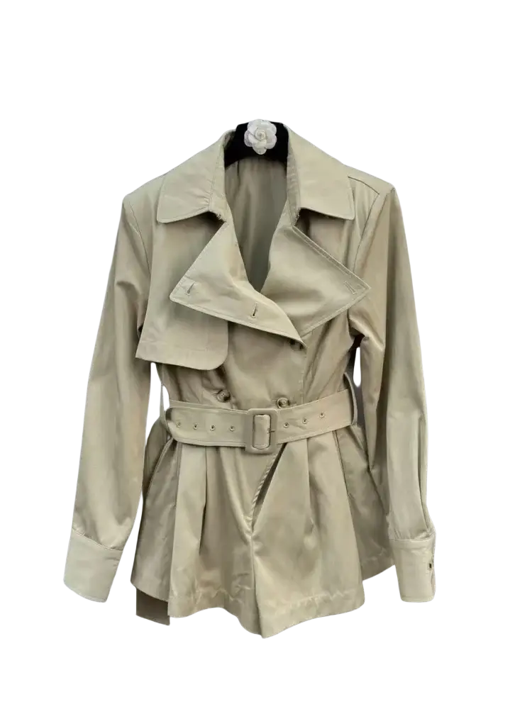 Beige belted trench coat with structured collar hanging on hanger suitable for elegant evening playsuit look