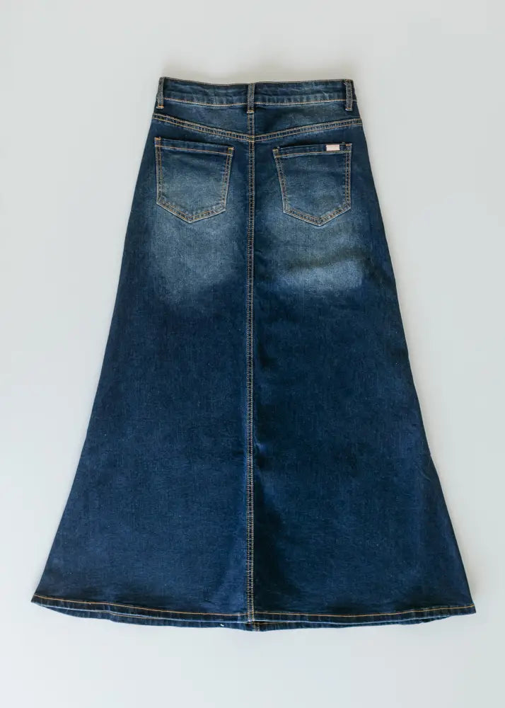 Bethany dark wash a-line denim maxi skirt in dark blue with a flared silhouette and two back pockets shown from the back