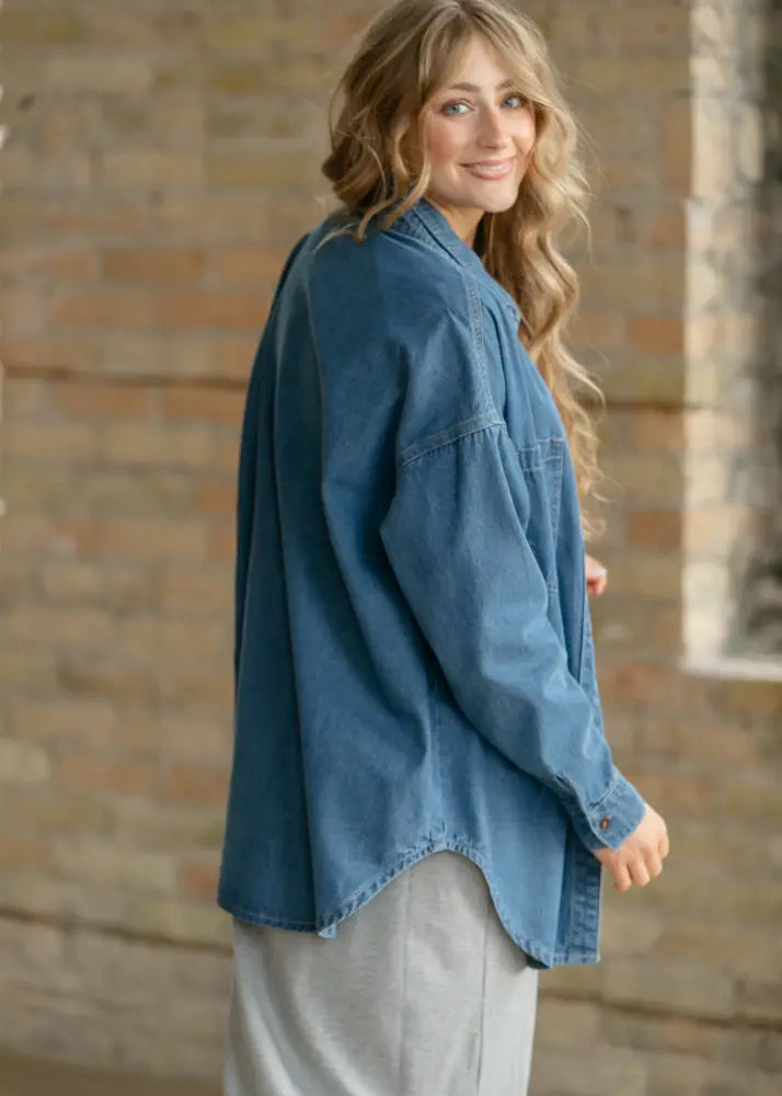 Betty denim relaxed button up shirt is a loose-fitting medium wash blue denim shirt with a frayed hem