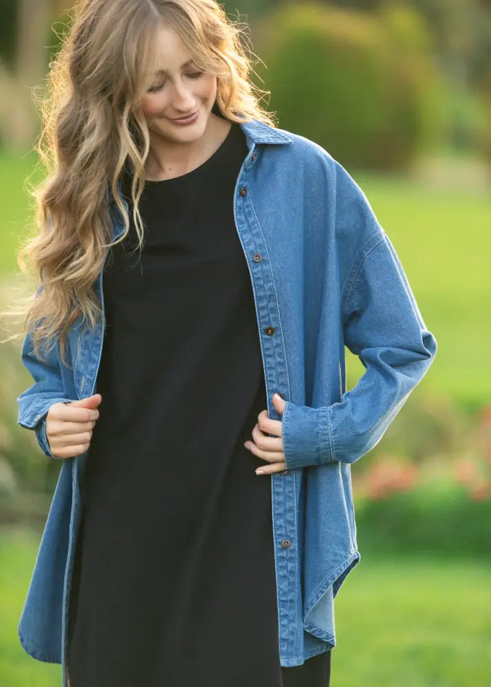 Blue denim betty denim relaxed button up shirt worn over a black dress showcasing casual layering style