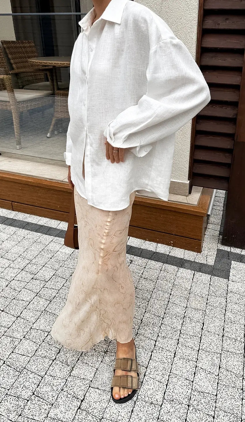 A loose-fitting white linen oversized textured button up cardigan blouse with long sleeves and a classic collar.