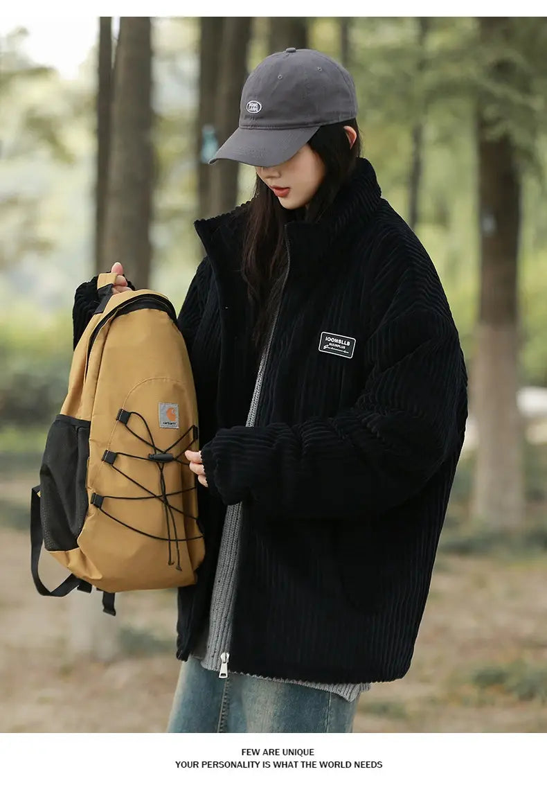Tanen und schwarze Carhartt-Rucksacktasche mit markantem Logo-Aufnäher vorne, kombiniert mit einer Herren Cord-Pufferjacke für den Winter als warmer Mantel.