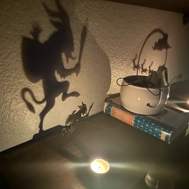 a white ceramic yarn bowl with a handle resting on stacked books shown alongside a halloween bat candle holder black metal shadow decor