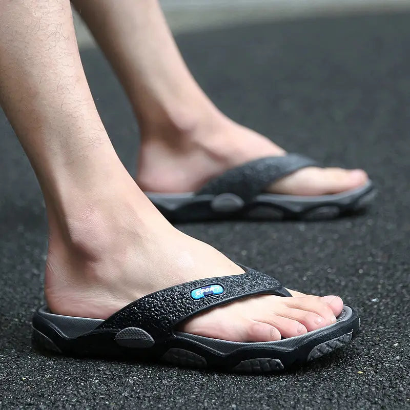 men’s non-slip beach flip flop with black textured strap featuring a blue logo and cushioned rubber sole for comfortable outdoor use