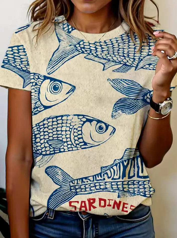 Beiges Damen-T-Shirt mit kurzem Ärmel und grafischem Motiv im Casual-Stil, mit einem blauen Fischdruck und dem Wort „Sardinen“ in roter Schrift am unteren Rand.