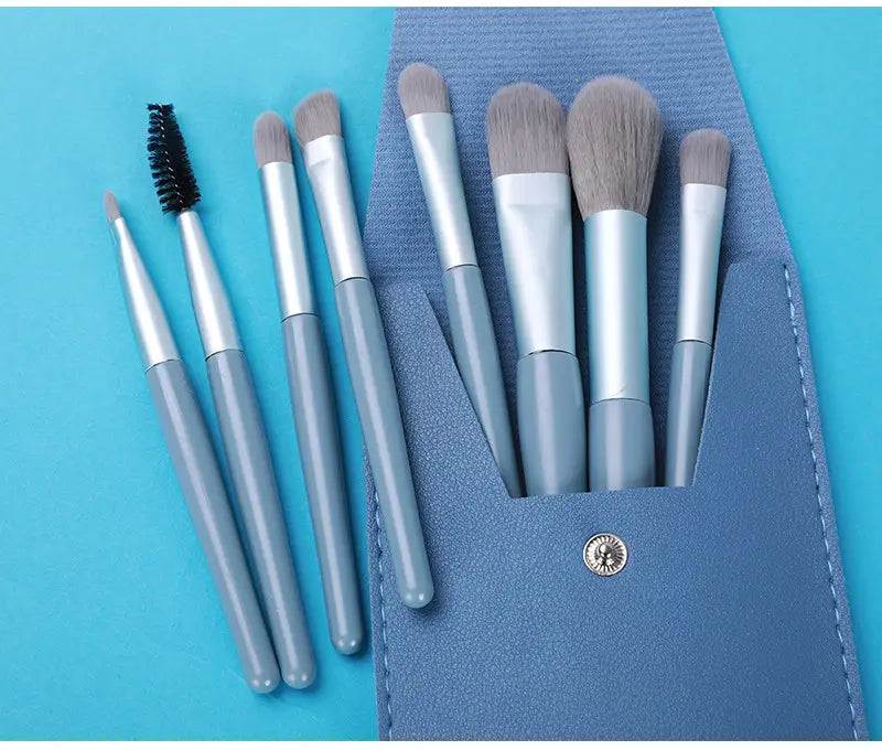 Set of seven gray and silver makeup brushes with soft bristles neatly arranged in a blue textured leather case from the makeup brush set with 8 pieces.
