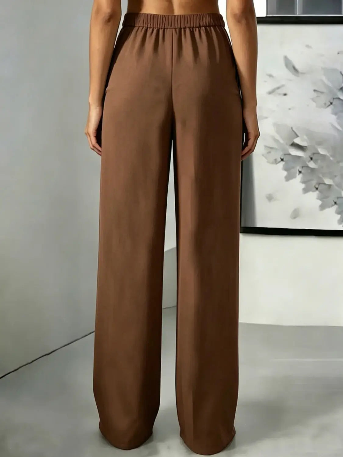 Pantalons bruns à jambes larges et taille haute avec des plis à l’avant et une ceinture élastique conçue pour un port confortable et élégant.