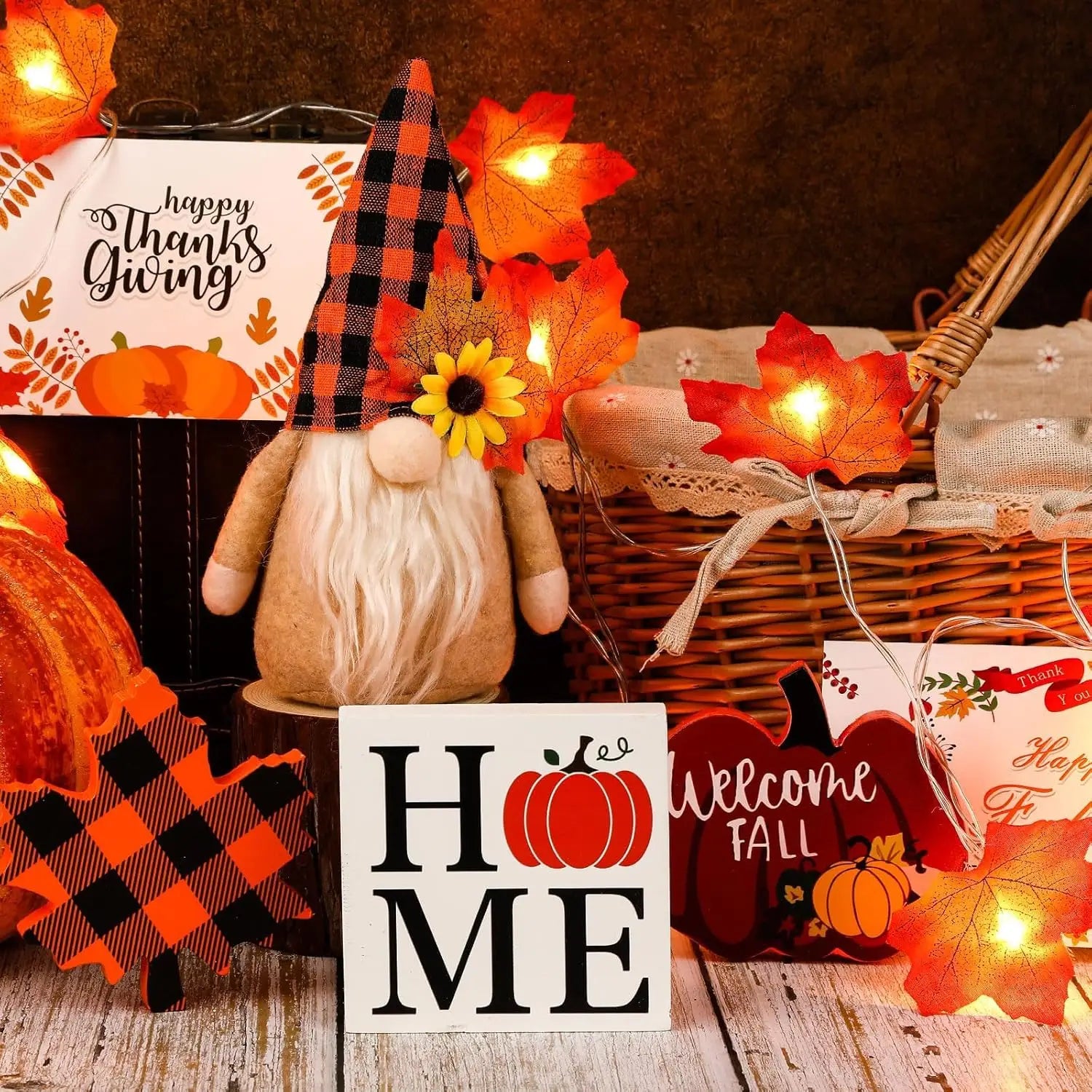 A plush autumn gnome with a beige fabric body, long white beard, and a black and orange plaid hat adorned with a yellow sunflower featured in a fall tiered tray decor set with gnomes and lights.