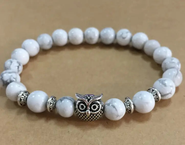 Natural lapis lazuli and lava stone owl charm bracelet featuring white marble beads with a silver owl charm and decorative metallic spacers.