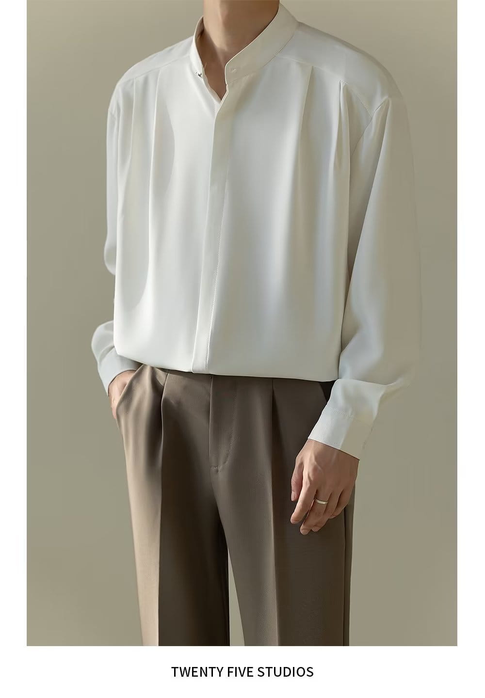 Chemise plissée pour homme à col montant blanche éclatante, présentant des manches longues boutonnées à l’avant et des plis subtils.