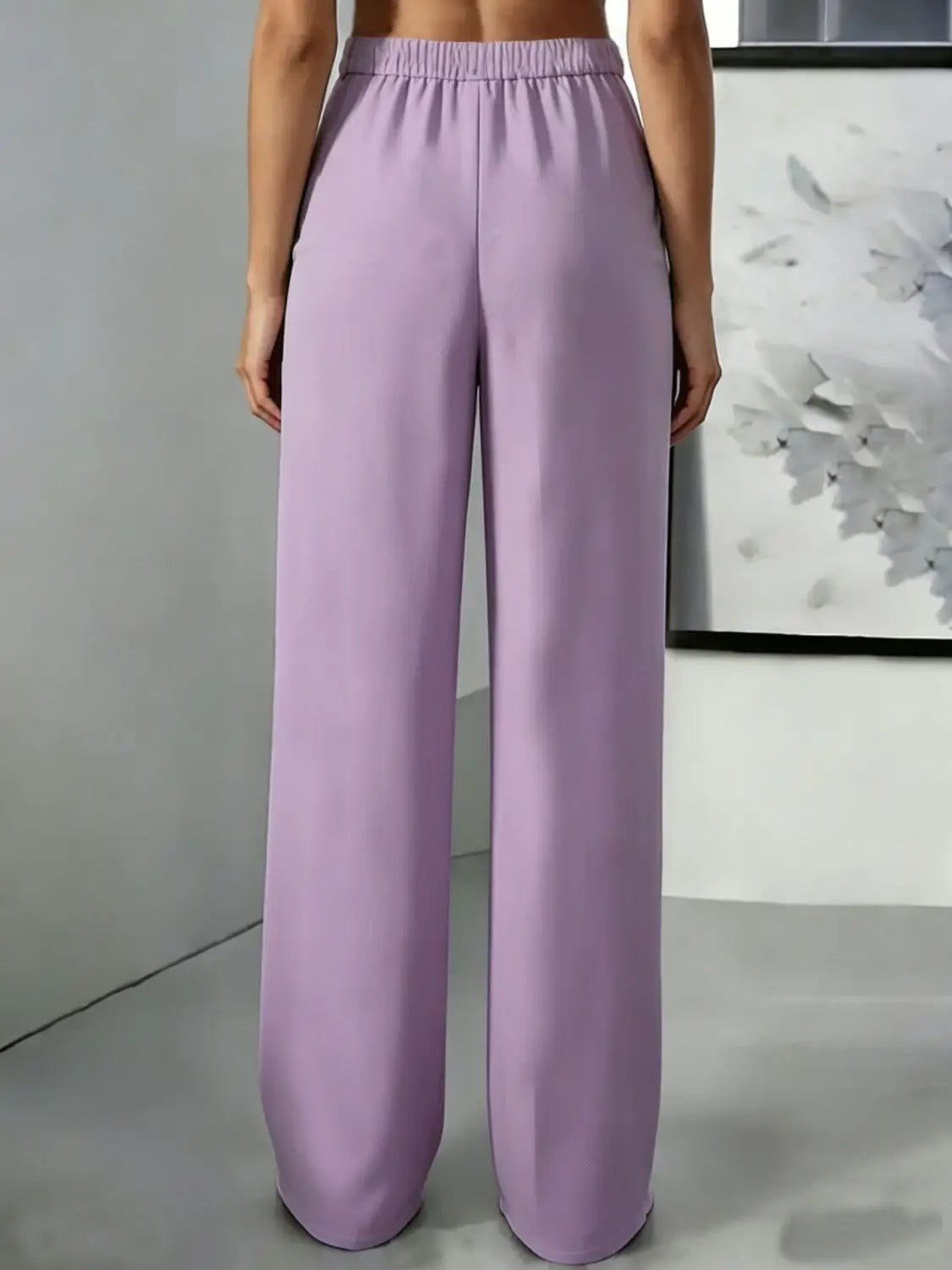 Pantalons lilas à jambes larges avec des plis à la taille haute et une ceinture élastique, réalisés dans un tissu léger pour un port confortable.