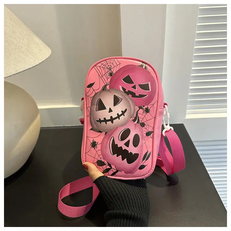 Pink embroidered Halloween floral and pumpkin crossbody bag with three smiling jack-o-lanterns and spiderweb patterns on soft fabric surface.