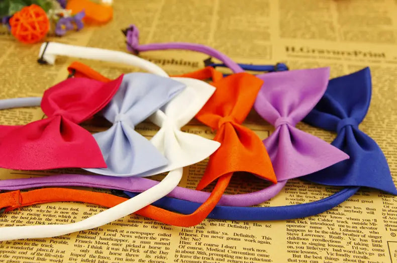 Una colección de collares para mascotas con lazos de color sólido ajustables, confeccionados con telas de colores en rosa, blanco, naranja, morado y azul