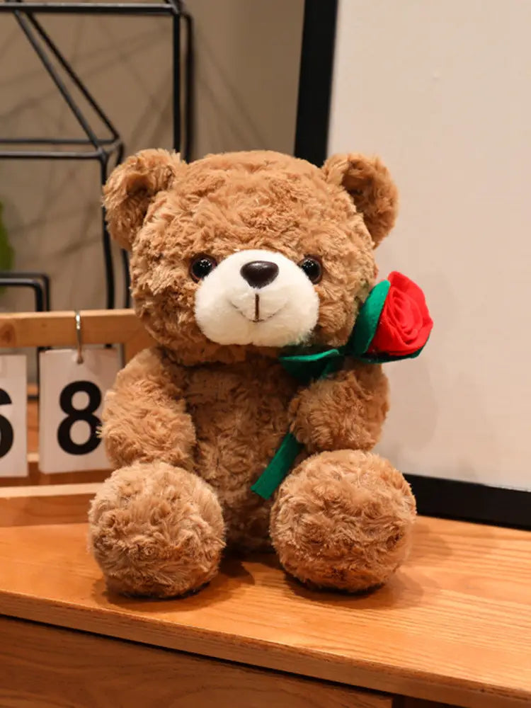 Ein brauner Plüsch-Teddybär mit weißer Schnauze und schwarzen Augen, der eine rote Rose mit grünem Stiel hält; Valentinsgeschenk in der Größe 16 bis 25 Zentimeter.