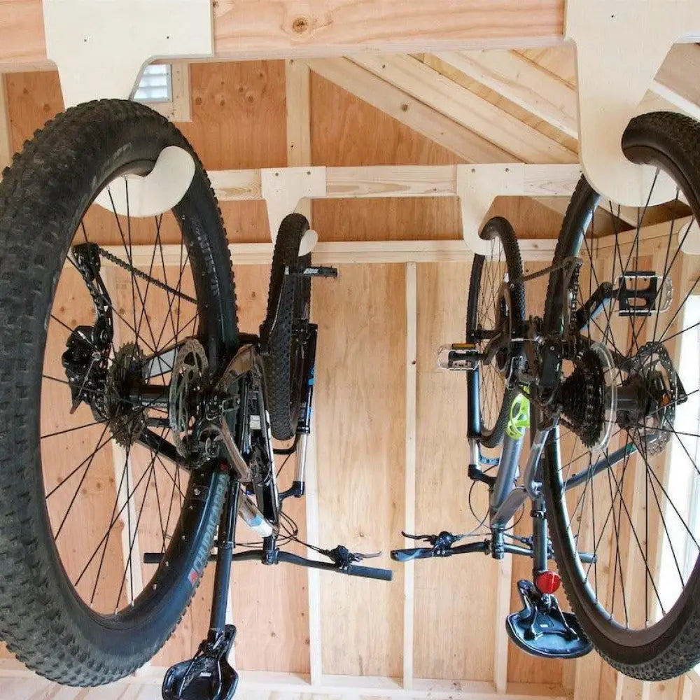 Heavy duty ceiling mount vertical bicycle storage hooks holding two upside down mountain bikes with metallic frames and black tires