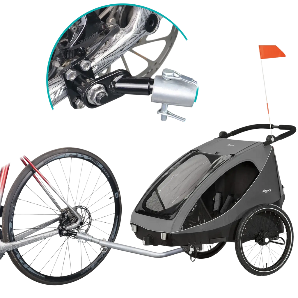 Gray and black child bike trailer with transparent front window attached to bicycle via silver metal hitch coupler adapter