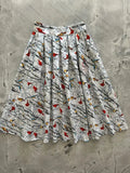 A white vintage pleated cotton skirt with pockets featuring a vibrant red cardinals and birds pattern on black branches