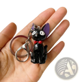 Black cat keychain with shiny enamel finish featuring purple ears and red bow made of pvc for bag charm use
