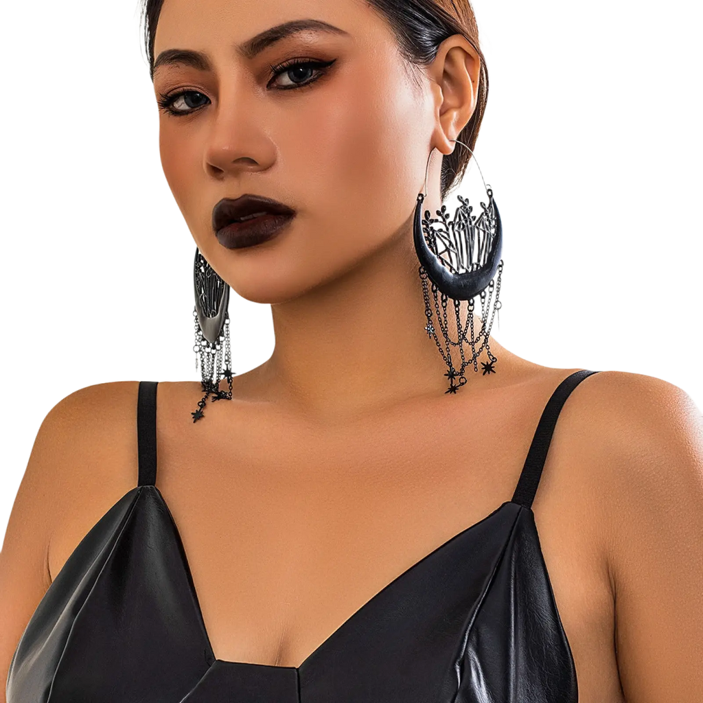 Black crescent moon tassel earrings featuring intricate filigree detailing and dangling star chains in black metal