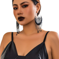 Black crescent moon tassel earrings featuring intricate filigree detailing and dangling star chains in black metal