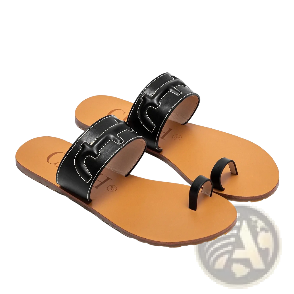 Black leather flat sandals with distinctive t-shaped straps and tan rubber soles for casual wear