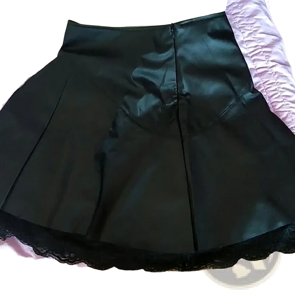 Black leather pleated skirt with shiny faux leather finish and delicate black lace trim along the hem