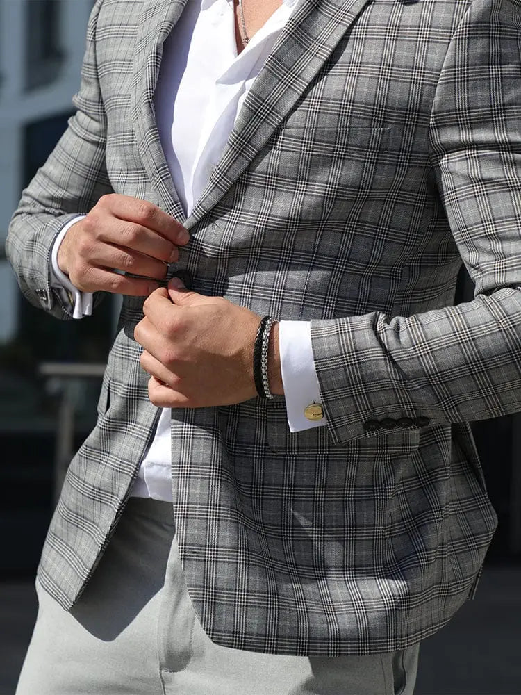 Black braided leather and silver box chain bracelet displayed on gray plaid blazer with black and white intersecting lines
