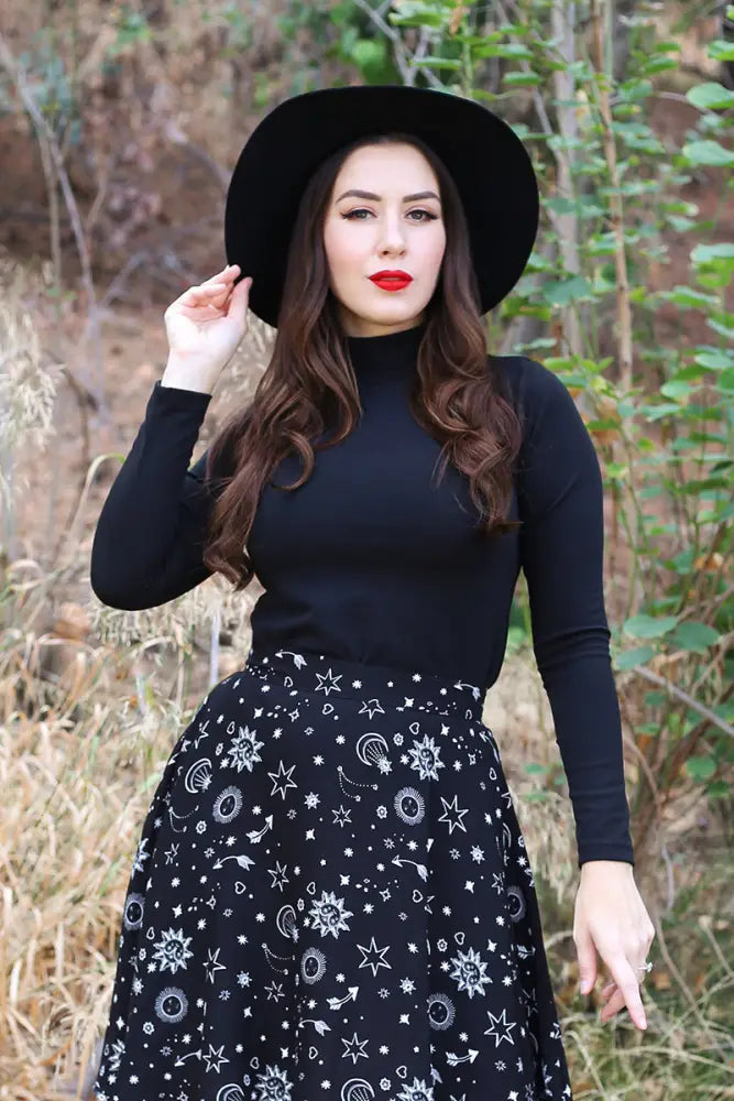 Vintage black long sleeve mock neck stretch top paired with a black high waisted skirt featuring white celestial patterns