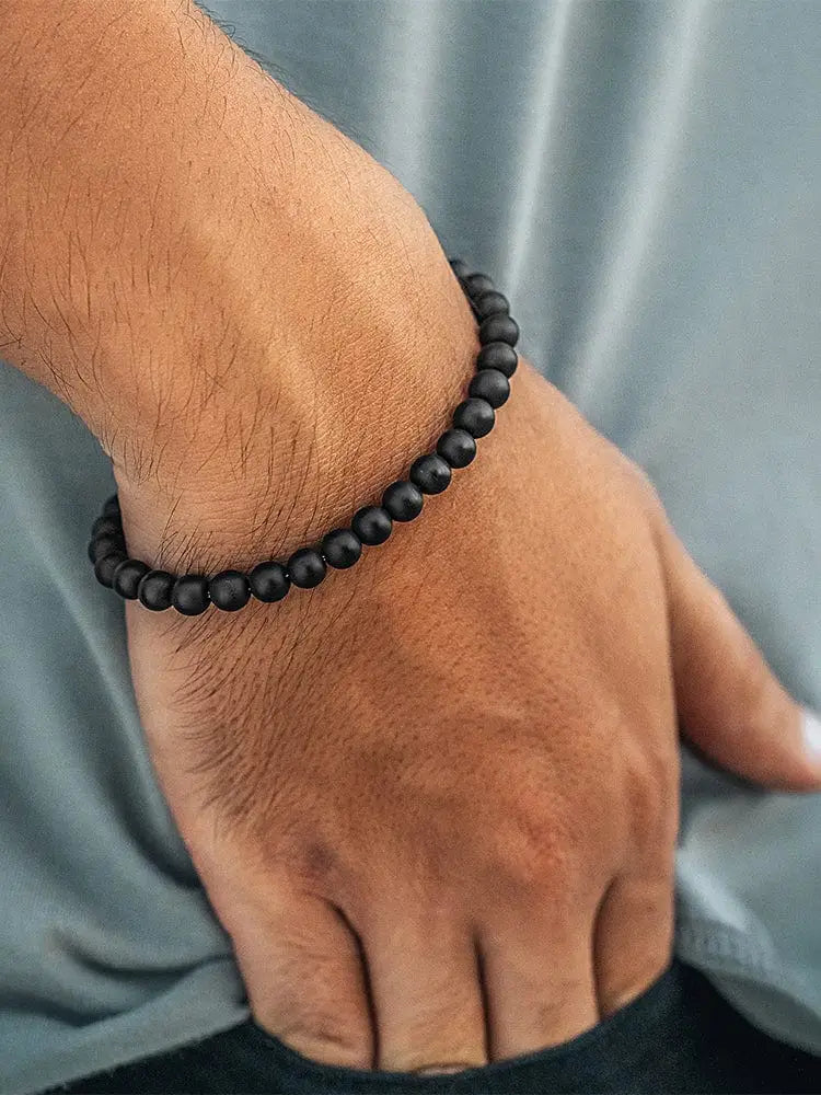 Matte black onyx beaded bracelet with greek key accents worn on wrist showcasing black polished beads
