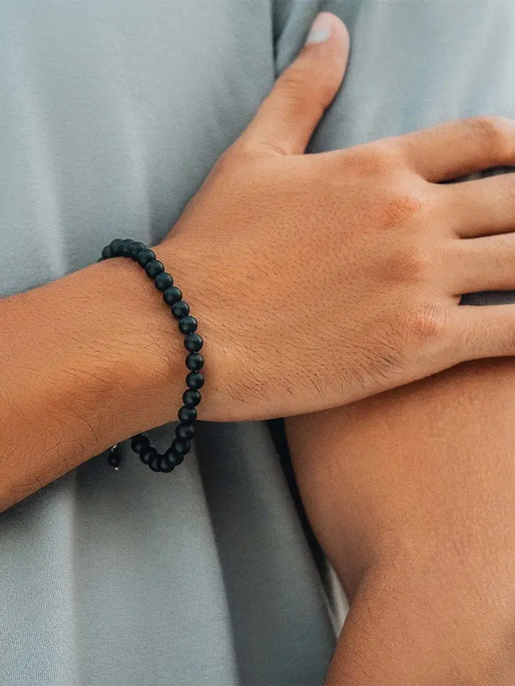 Matte black onyx beaded bracelet with greek key accents worn on a wrist showcasing its elegant design