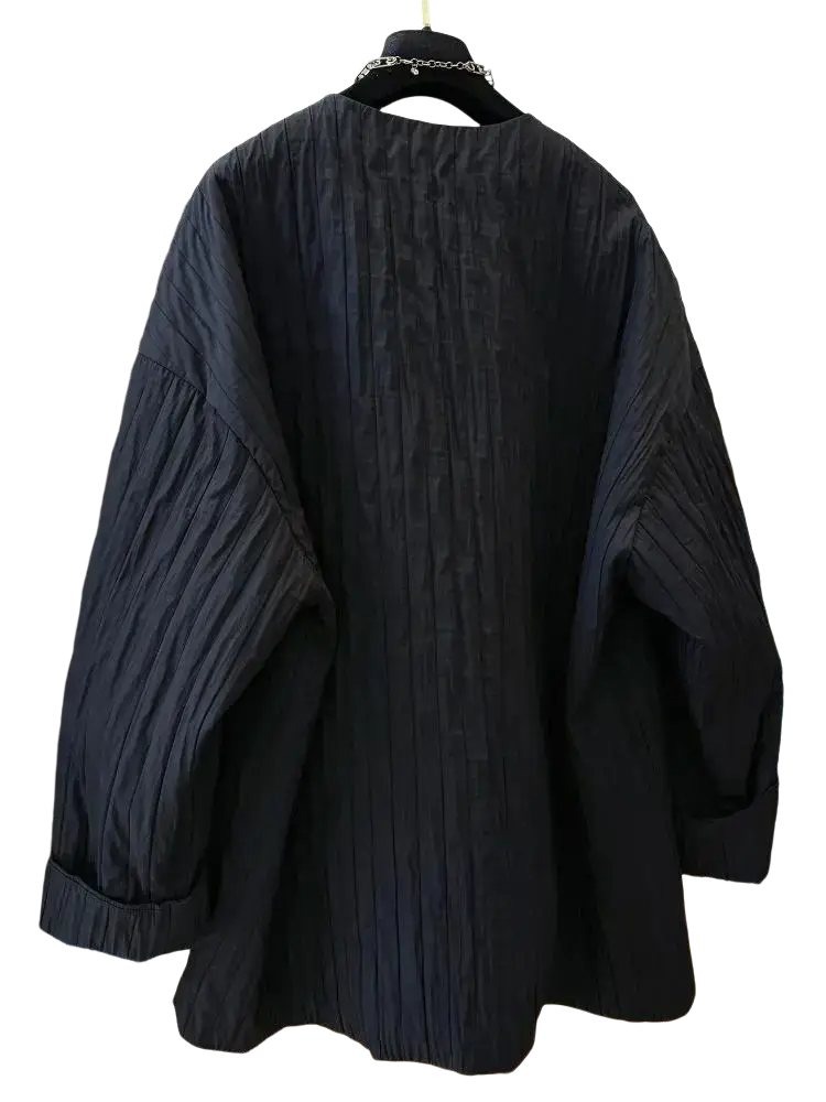 Black quilted puffer winter parka jacket with relaxed black pleated cotton blouse and rolled cuffs visible