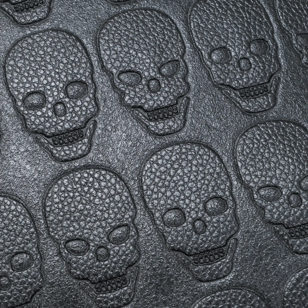 Black studded skull leather commute backpack featuring black textured leather with embossed skull patterns