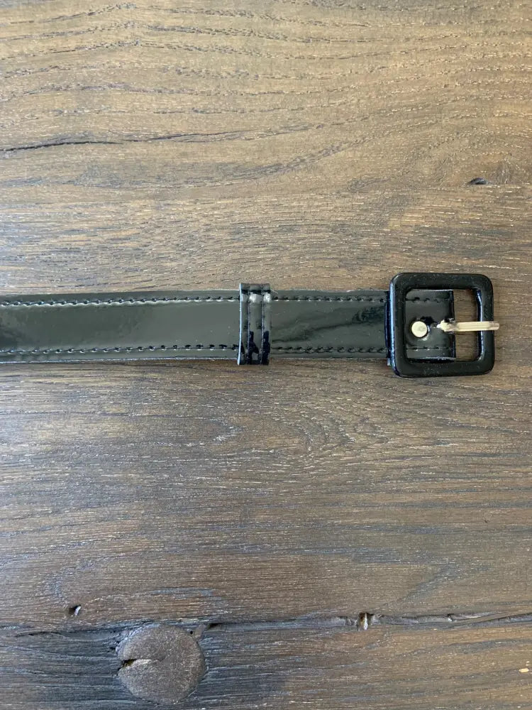 Retro black patent vinyl belt with silver eyelets featuring a black patent leather strap and gold-tone square buckle