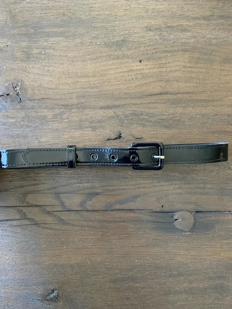 Retro black patent vinyl belt with silver eyelets featuring a sleek rectangular buckle and evenly spaced holes