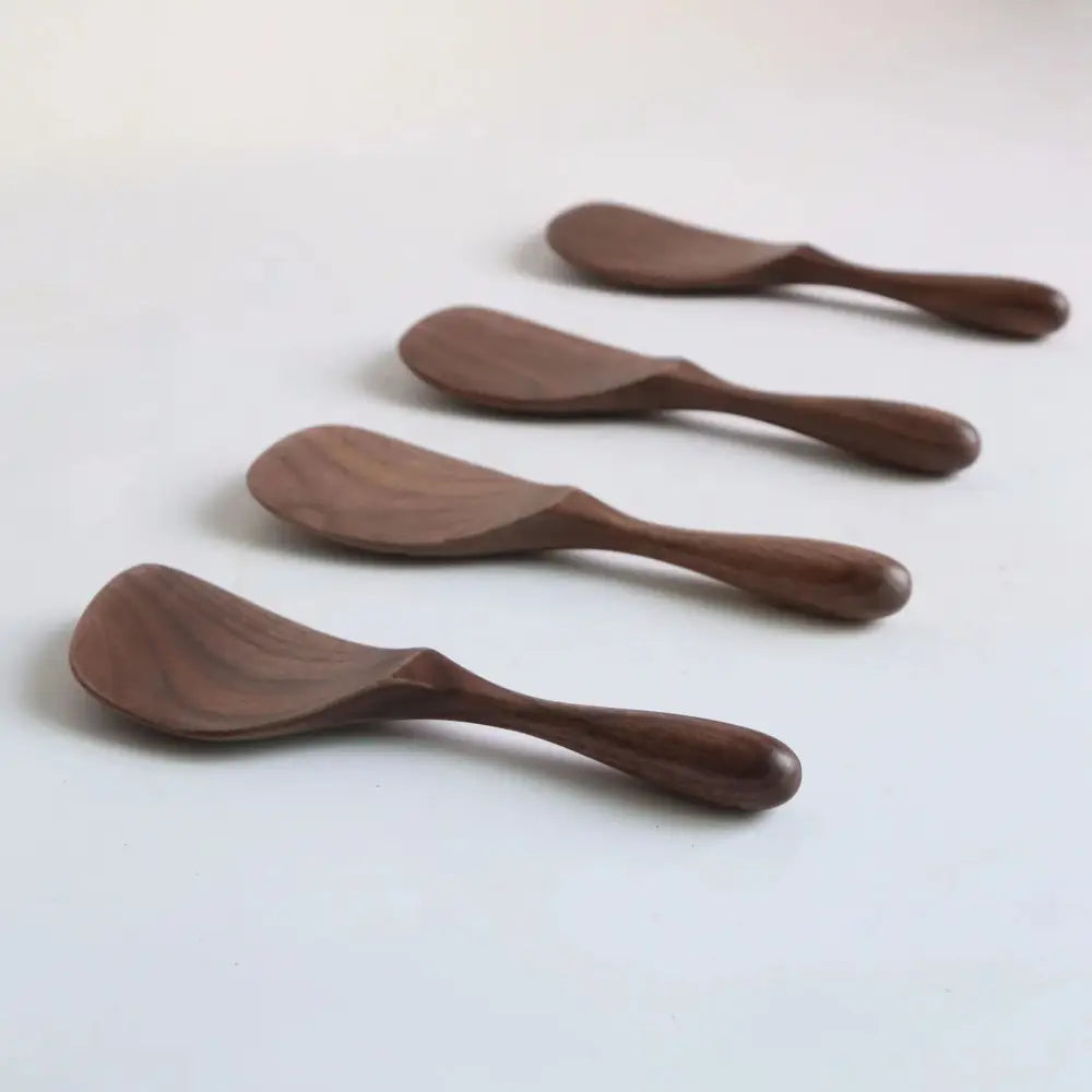 Set of four handcrafted dark brown black walnut wood butter knives with smooth rounded handles and curved blades