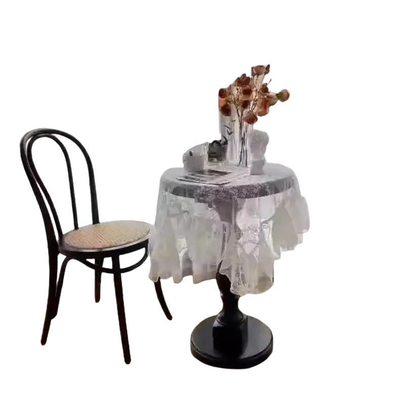 Black wrought iron round accent table with ornate base and white lace tablecloth draped over it