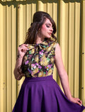 A vibrant sleeveless top with a black base and metallic gold purple green floral pattern featuring a bow neckline