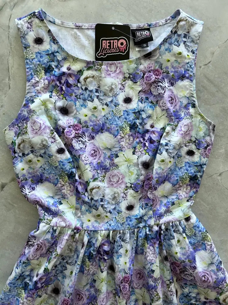 A sleeveless vintage 1950s floral cotton midi dress in soft lavender blue and white with gathered waist and ruffled skirt