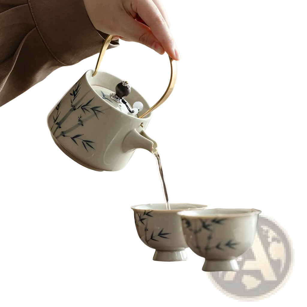 A white ceramic blue bamboo teapot set with polished gold handle being poured into matching cups