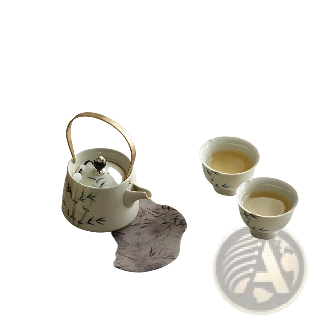 White ceramic blue bamboo teapot set with gold handle and bamboo leaf design on gray fabric mat
