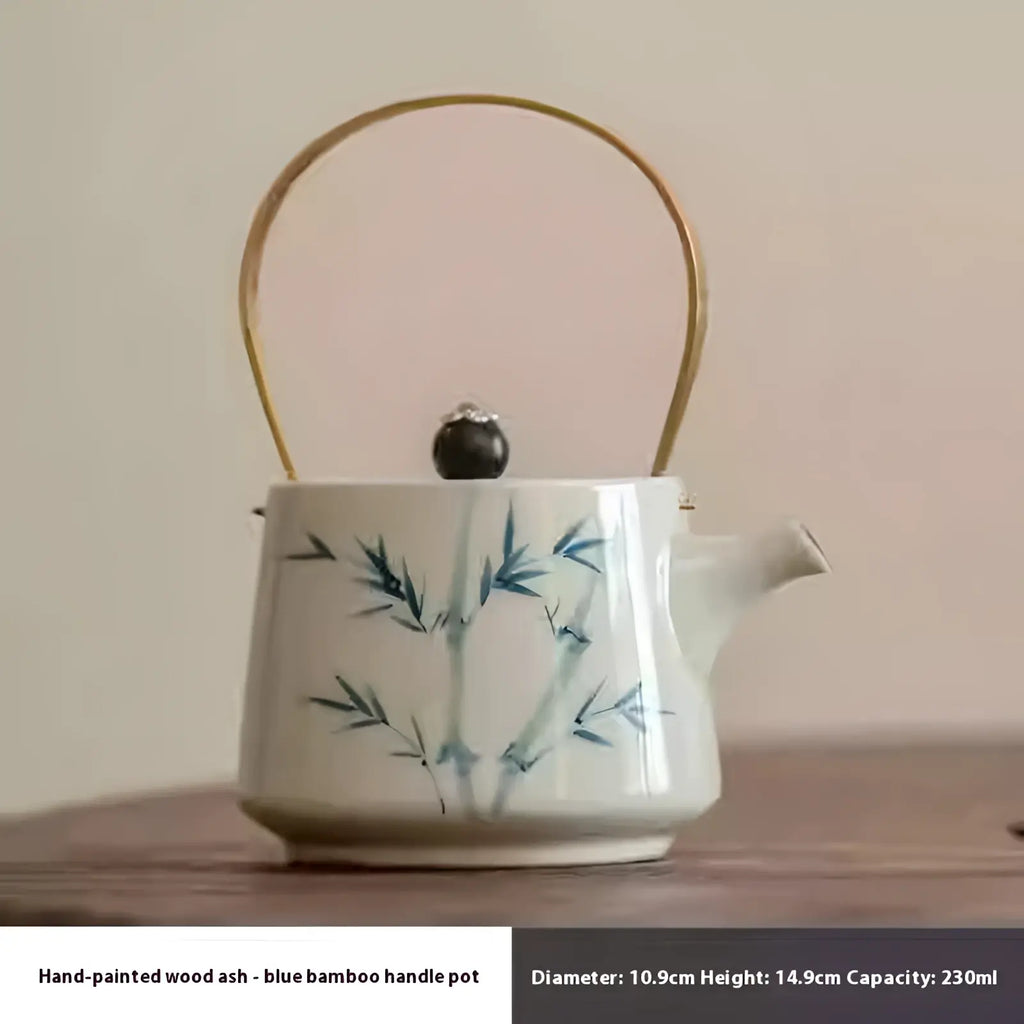 White ceramic teapot with hand-painted blue bamboo motifs gold-toned metal handle and dark wooden lid knob in blue bamboo set