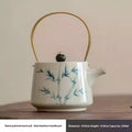 White ceramic teapot with hand-painted blue bamboo motifs gold-toned metal handle and dark wooden lid knob in blue bamboo set
